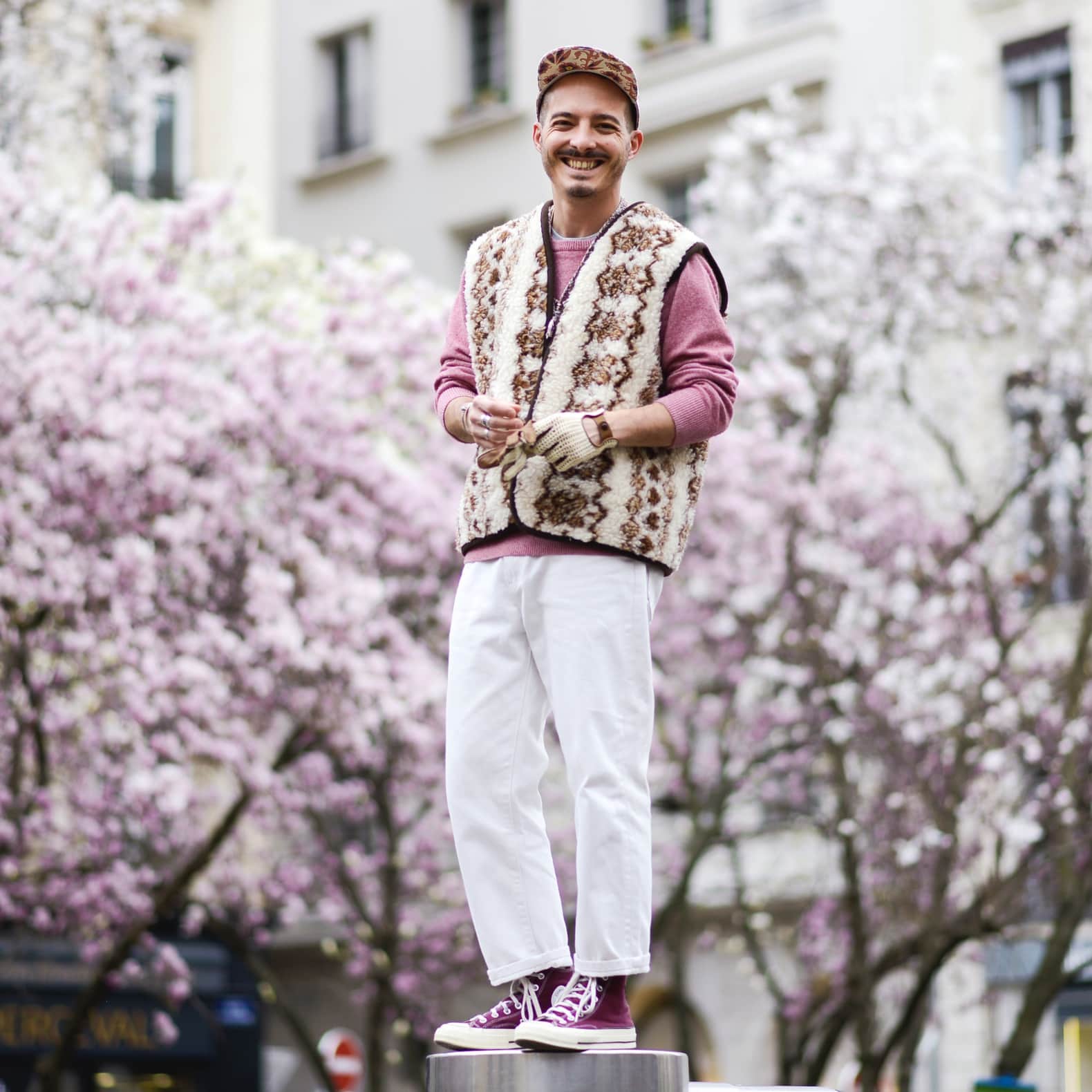 homme en pantalon blanc jean et sweat rose avec un gilet en mouton et des converse violette