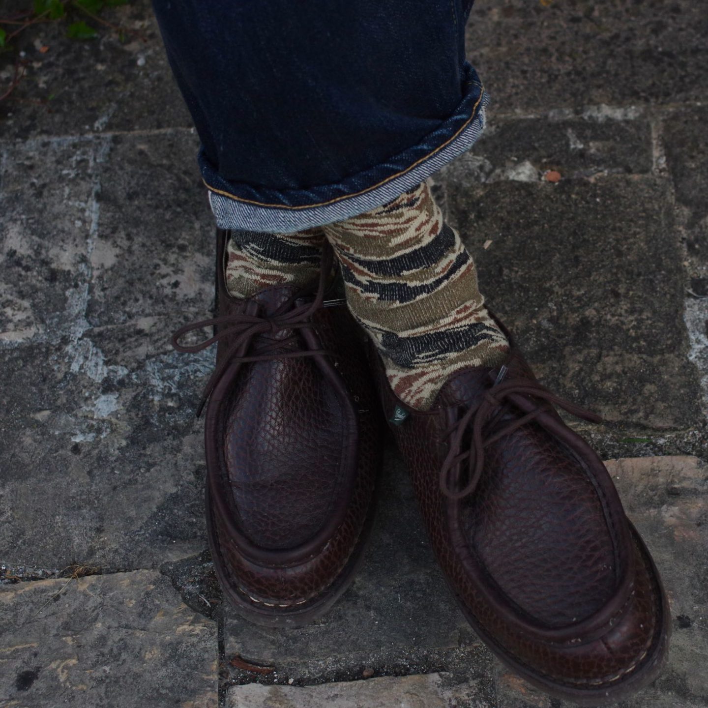 une paire de chaussette de la marque japonaise Anonymous ism avec un imprimé camo tiger stripe et de belles paraboot michael bison