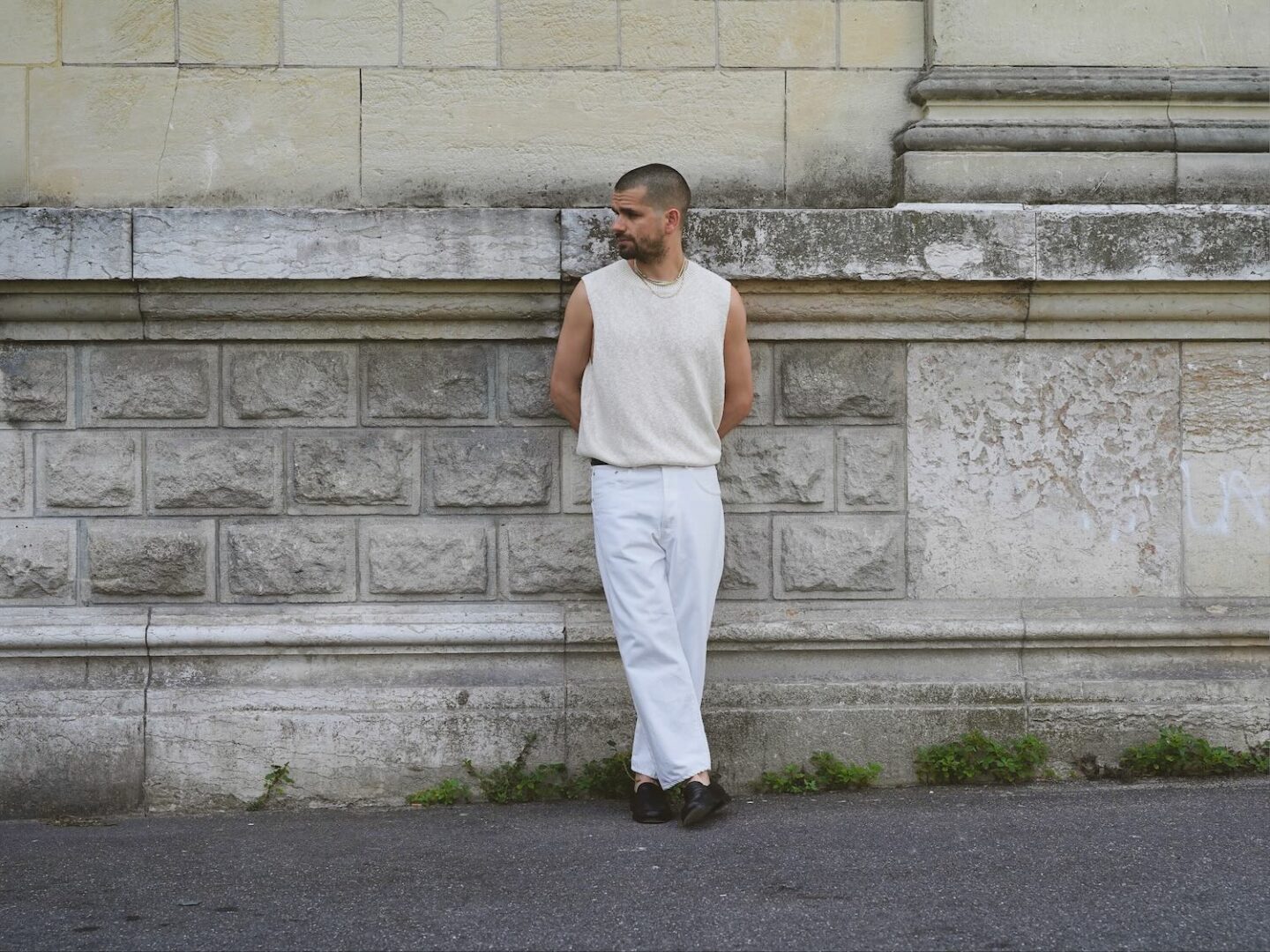 mens outfit with knitted tank top tucked in high wast white jeans and black loafers