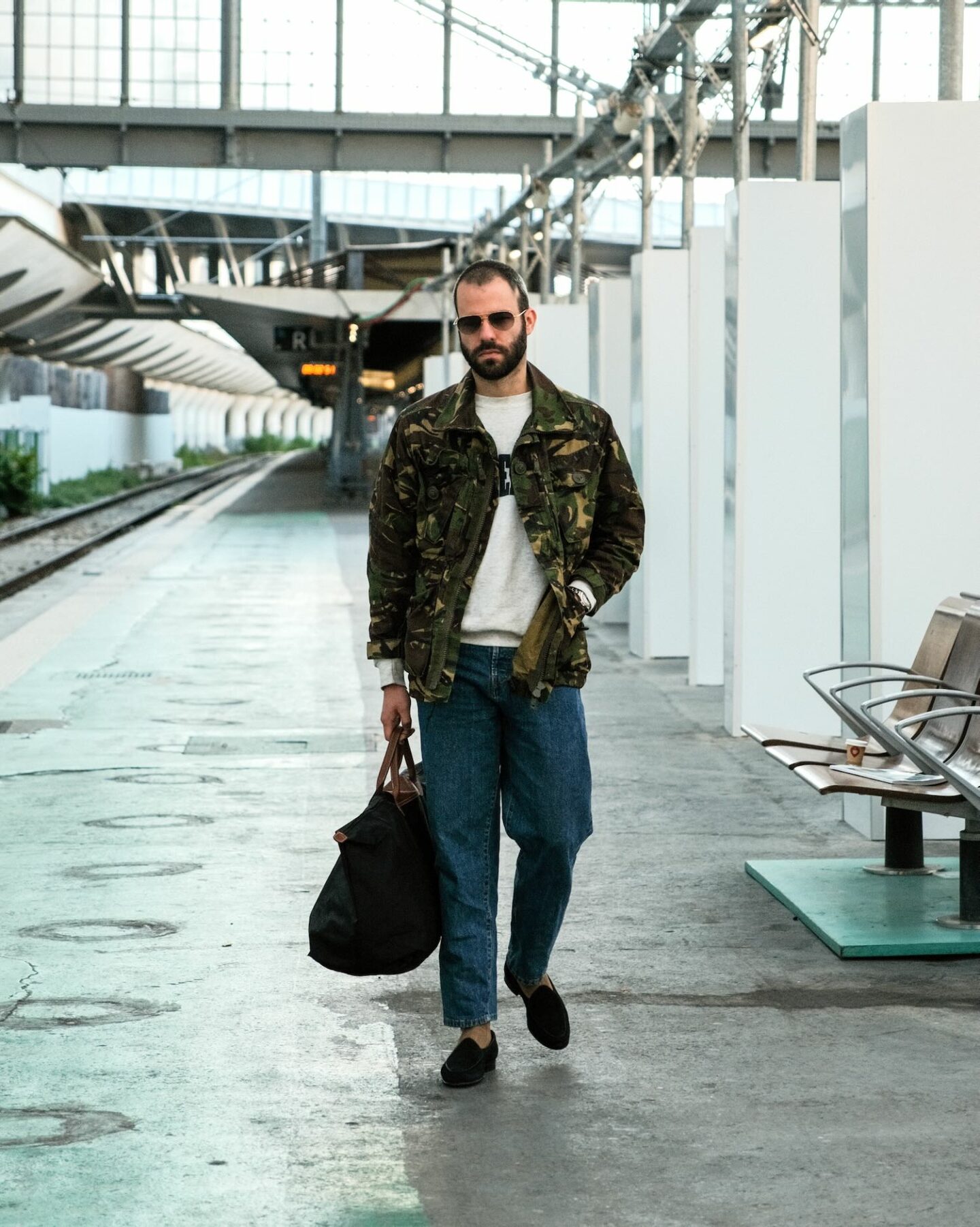 tenue de voyage avec un jean taille haute borali, des belgian loafers et un veste militaire camo