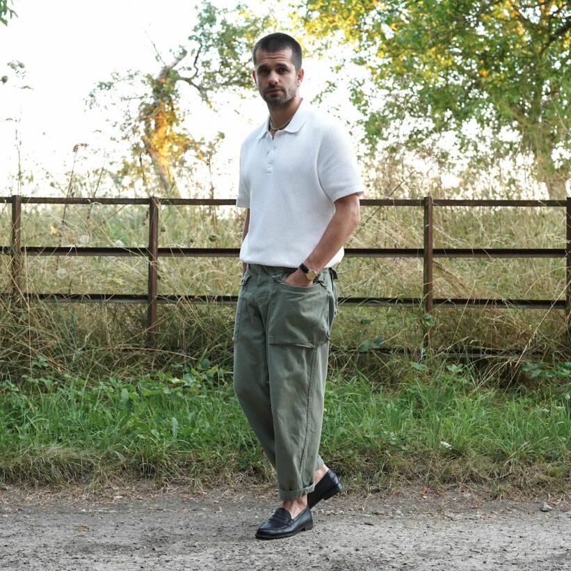 look d'été homme avec un polo en maille texturée, un pantalon militaire et des mocassins noirs