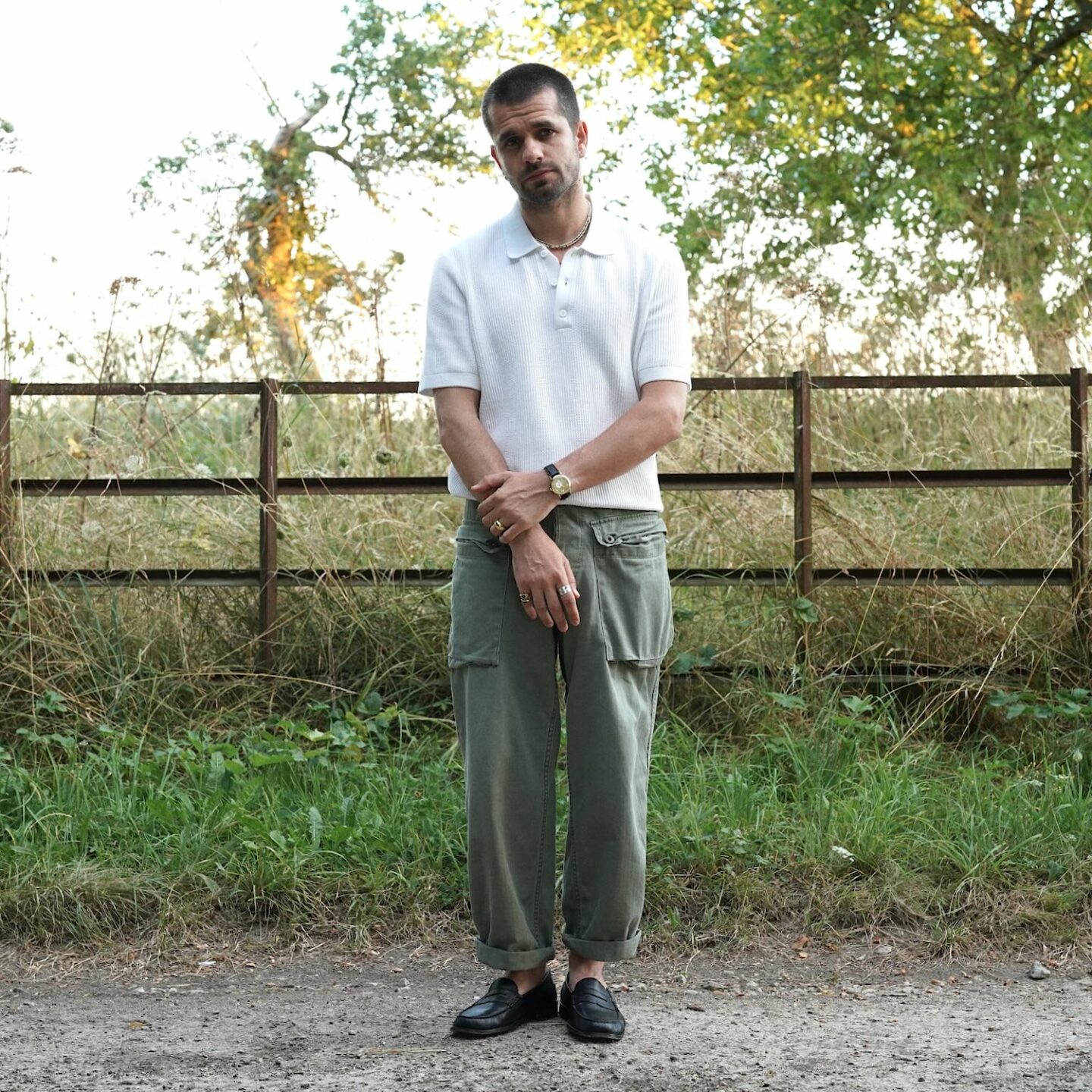 look d'été homme avec un polo en maille texturée, un pantalon militaire et des mocassins noirs