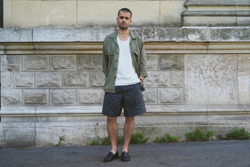 tenue d'été pour forte chaleur avec une surchemise militaire Arashi Denim en popeline tropiquale, un short et un débardeur COS, ainsi que des mocassins Malfroid Vauban