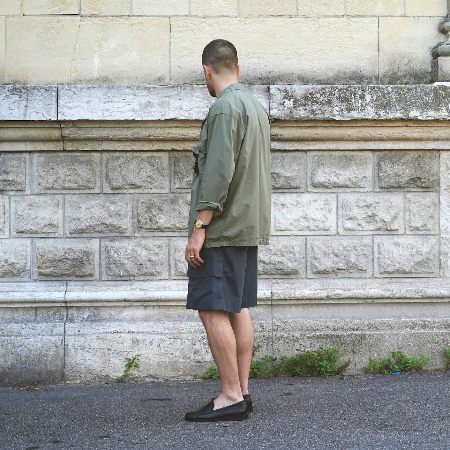 tenue d'été avec une surchemise militaire en popeline de coton tropical, portée avec un débardeur blanc, un short cargo et des mocassins noirs