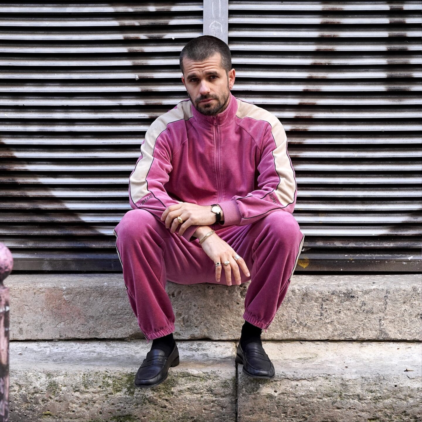 mens outfit who wers track patns and jacket in pink velbvet fabric from Supreme, with black loafers from malfroid