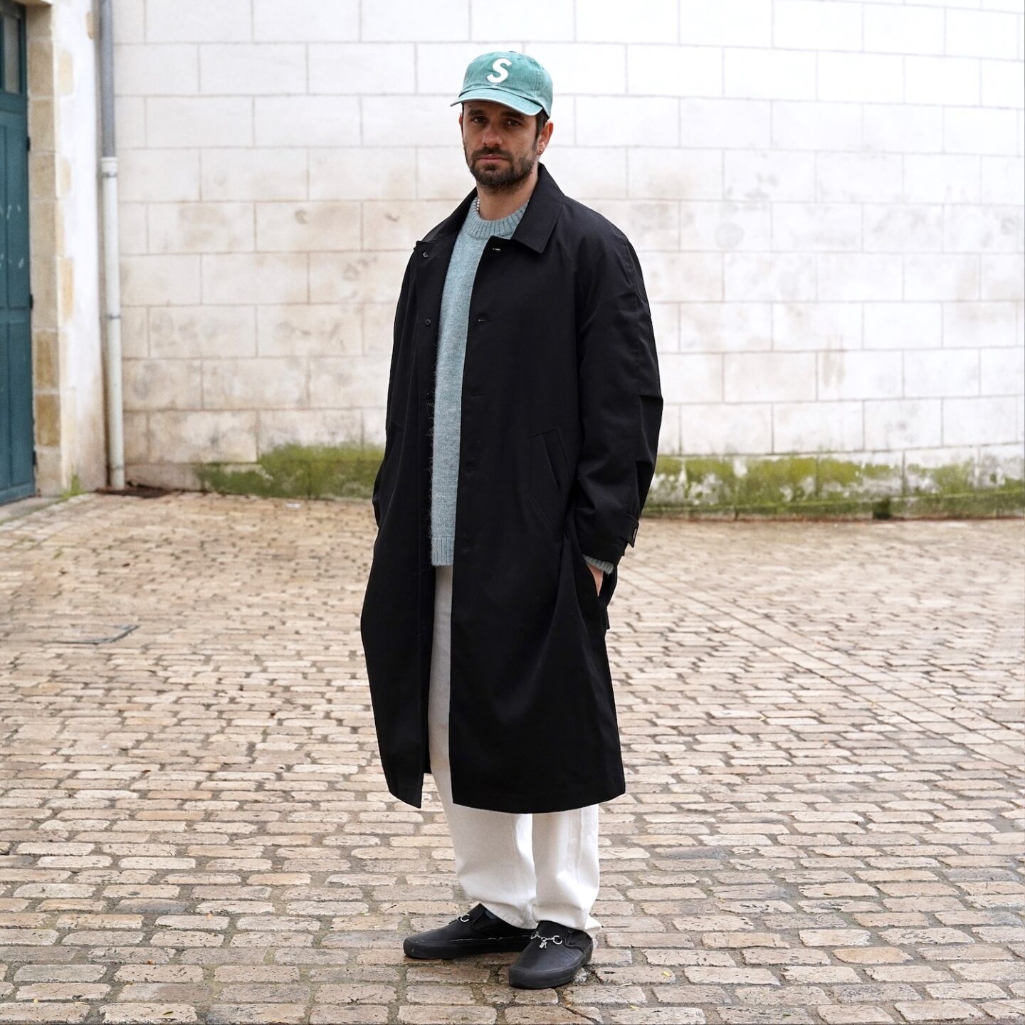 tenue homme avec un jean blanc taille haute de la marque Borali, un trench noir Coltesse, un pull en laine d'alpaga COS et des vans slipon