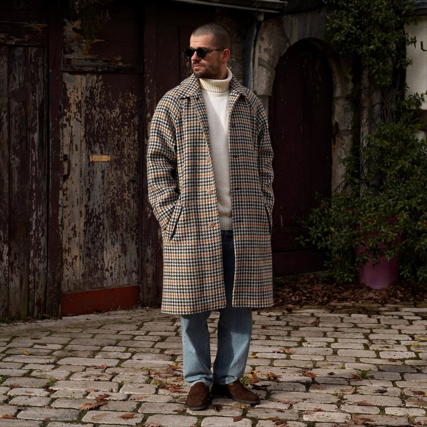 tenue homme avec un manteau en laine long à motif pied de poule et porté avec un jean clair et des mocassins marron