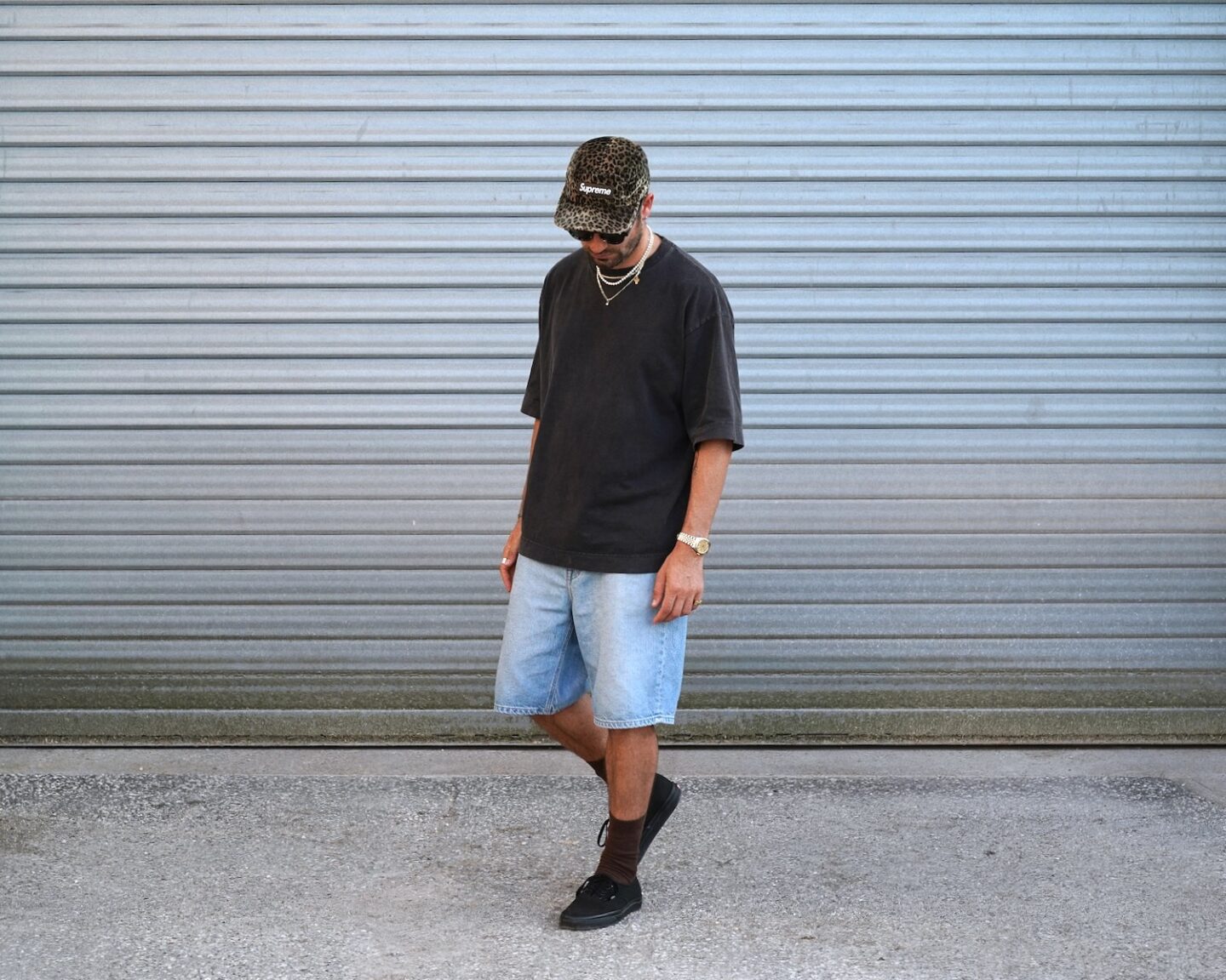 look d'été inspiration skate avec t-shirt oversize drapeau noir, short en denim lee et vans era