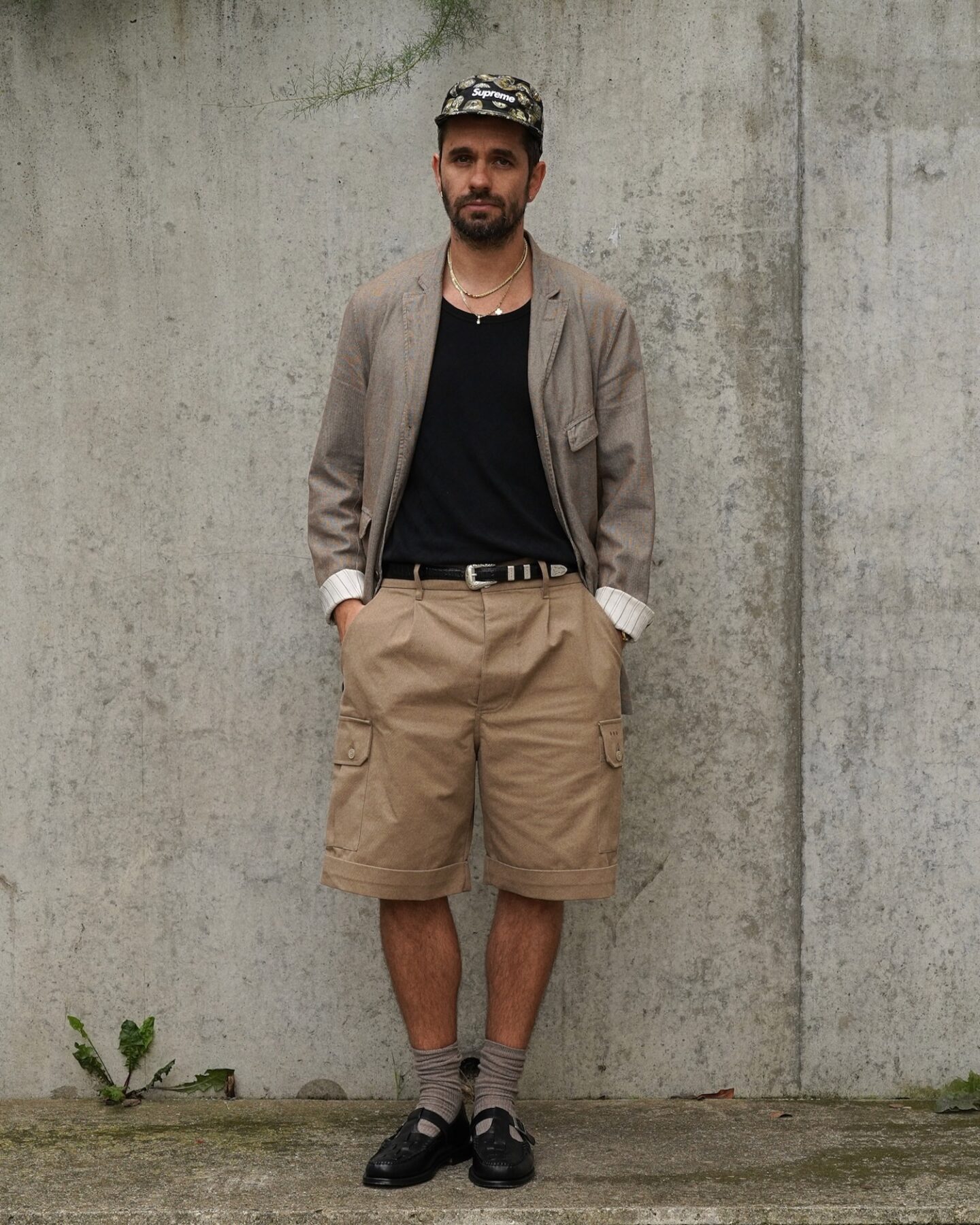 tenue masculine d'été où se mélange des vêtements élégants comme le blazer à des pièces plus street comme une casquette Supreme ou encore du workwear avec un short cargo