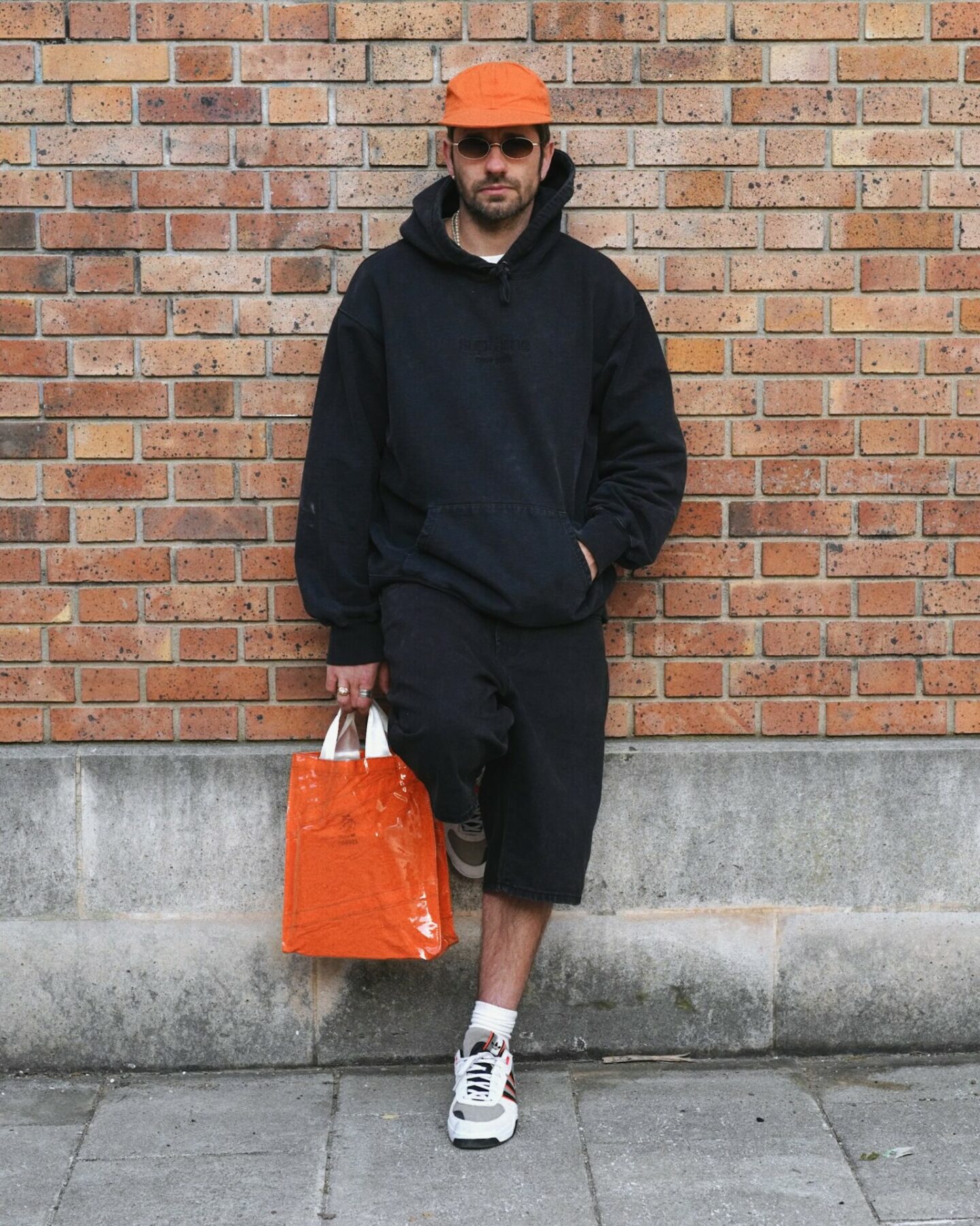 tenue d'inspiration skate avec un hoodie et short baggy noir SUpreme, des adidas retro et une casquette atelier dnhn