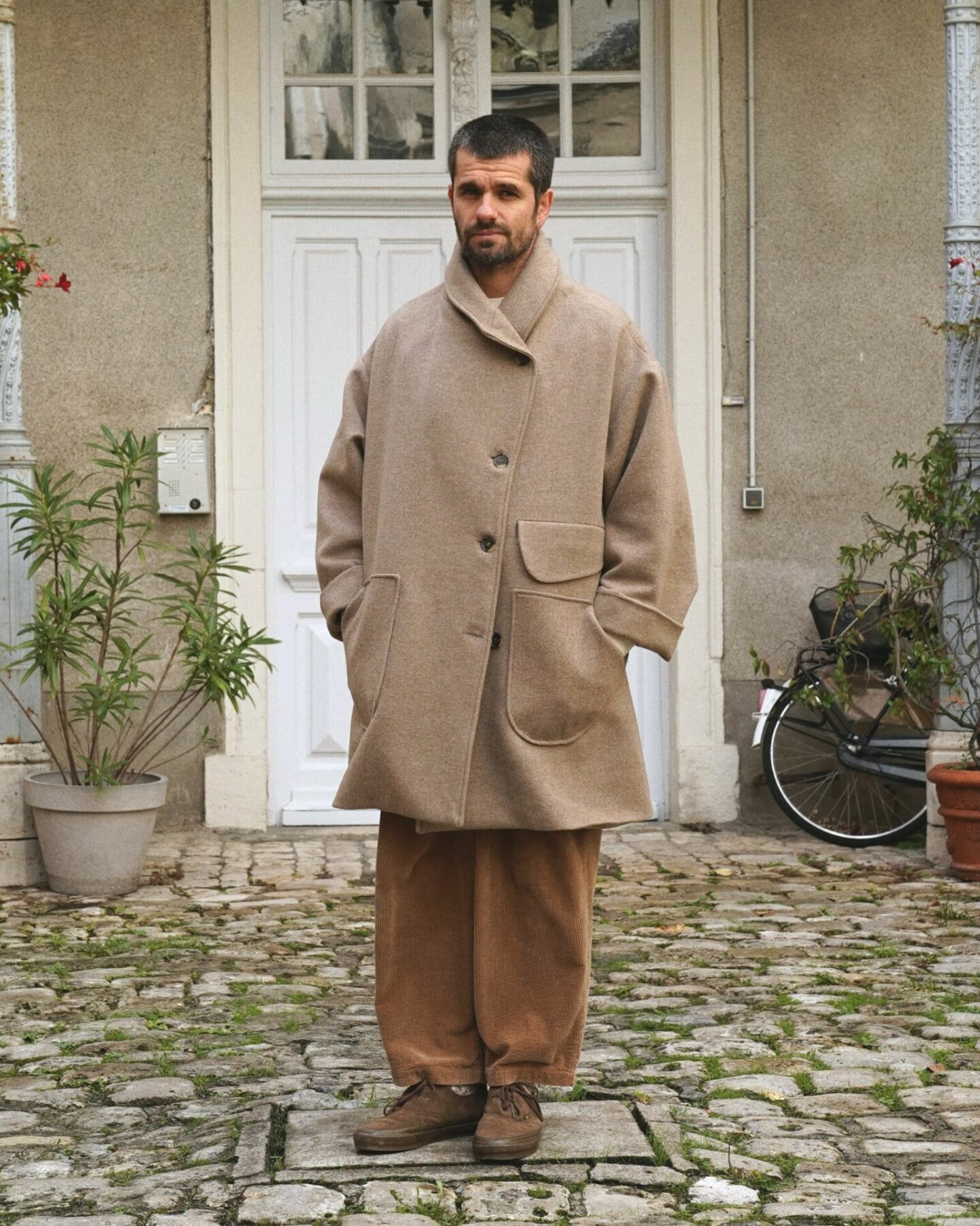manteau en laine et en cachemire de la marque Aïdama, coupe oversize unisexe, modèle Haomi et porté avec un pantalon borali en velours et des vans rease