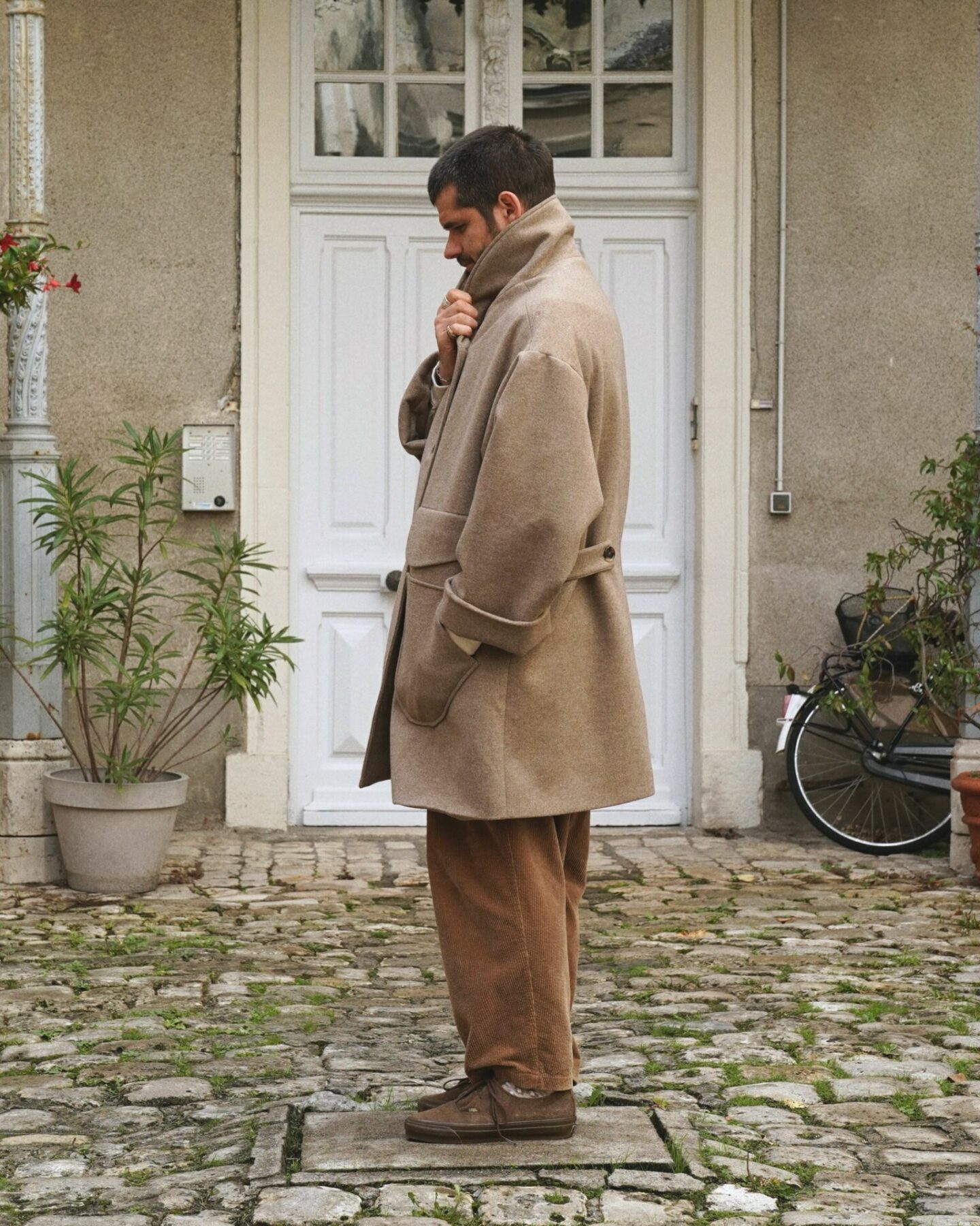 manteau en laine et en cachemire de la marque Aïdama, coupe oversize unisexe, modèle Haomi et porté avec un pantalon borali en velours et des vans rease
