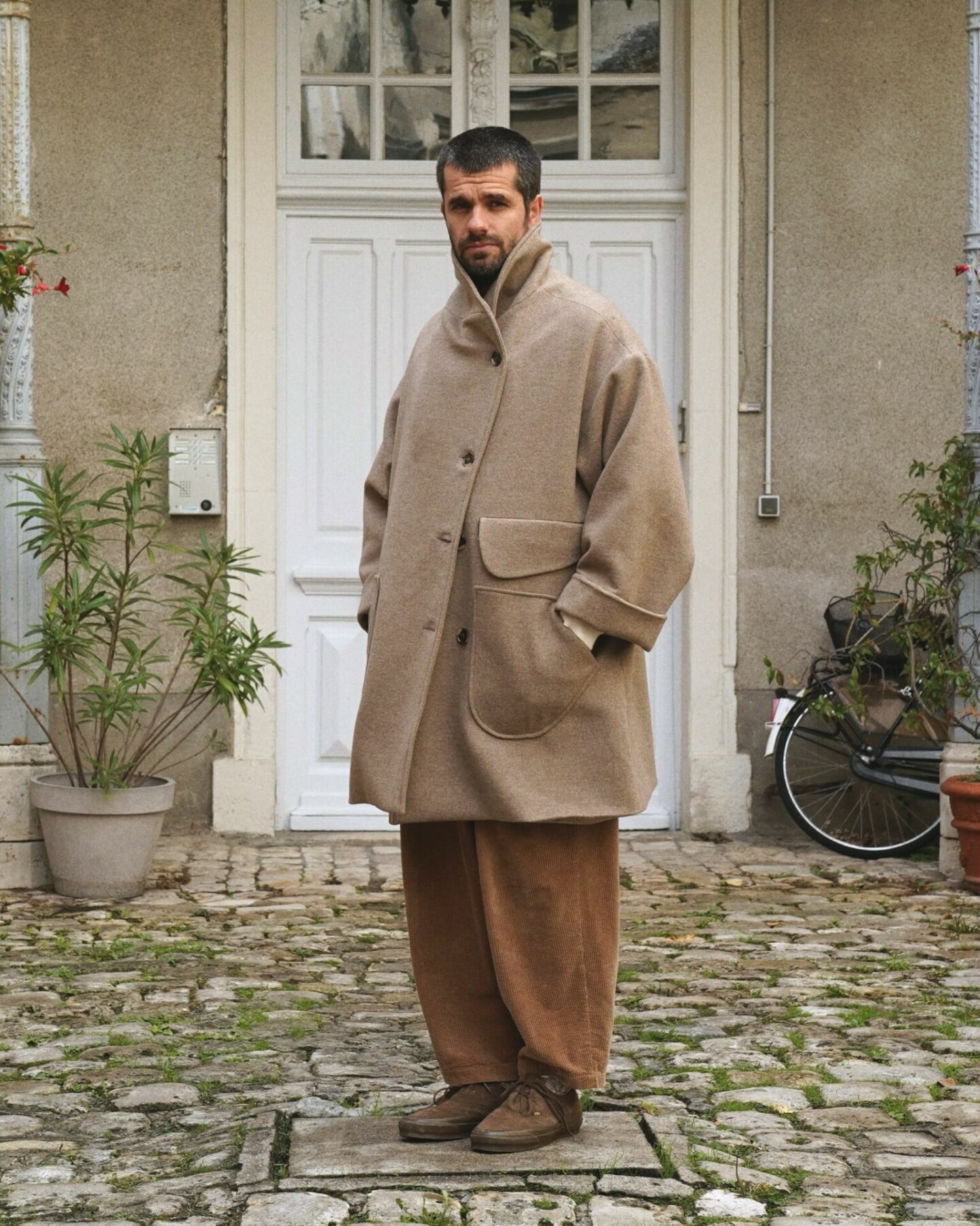 manteau en laine et en cachemire de la marque Aïdama, coupe oversize unisexe, modèle Haomi et porté avec un pantalon borali en velours et des vans rease